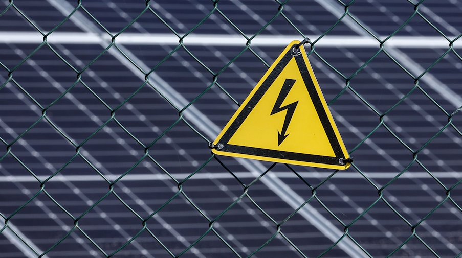 A warning sign warns of high voltage current at the new photovoltaic plant Peres II in the former open pit mine. / Photo: Jan Woitas/dpa