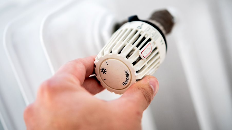 A man turns the thermostat of a heater in an apartment. / Photo: Hauke-Christian Dittrich/dpa/Symbolic image