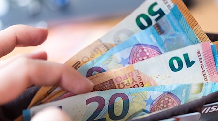 A woman holds a purse with banknotes in her hand / Photo: Monika Skolimowska/dpa/Symbolic image