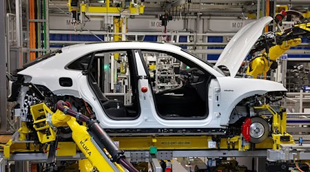 Industrijełaki roboter dźěłaju na wulłelektriskim Porsche Macan po křiśeńcu (zwjazk nowejaka a motora z karosou) w zakładźe Lipsk. / Foto: Jan Woitas/dpa
